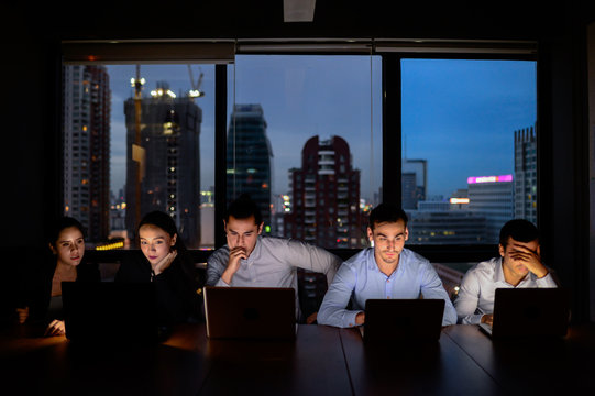 business team, three man and two woman working with computer overtime at night and low light