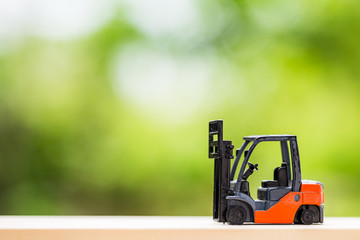 miniature toy forklift machine, over blurred green spring garden background.