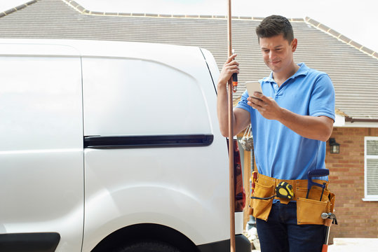 Plumber With Van Using Mobile Phone Outside House