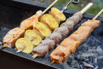 Grilling barbecue of fish, potato, pork and lula kebabs