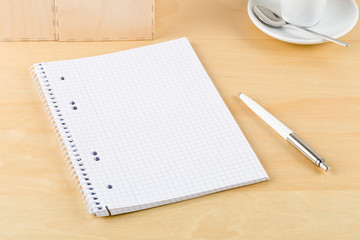 Brown wooden office desk with empty notepad, pen and cup