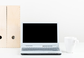 Office desk with cup, folders and laptop