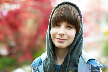 Outdoor handsome boy portrait. Teen boy in hoodie over spring park nature background.