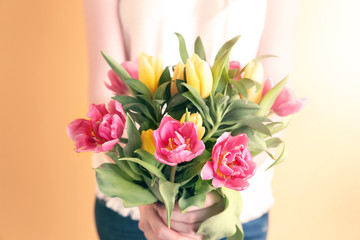 Woman holding beautiful bouquet on color background