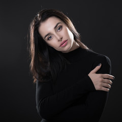 Fototapeta premium Beautiful girl posing over black background. Young pretty woman in studio.