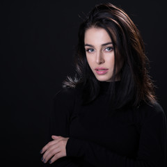 Naklejka premium Beautiful girl posing over black background. Young pretty woman in studio.