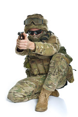 Fototapeta premium Military man in camouflage uniform, armor vest, dark glasses and helmet with gun aiming at the enemy