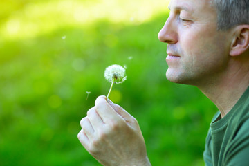 Man with dandelion over blured green grass, summer nature outdoor