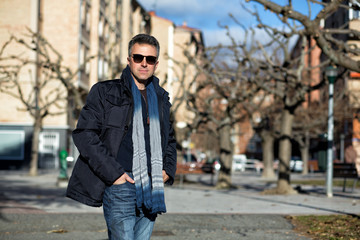 Fototapeta na wymiar Handsome happy smiling man. Outdoor winter male portrait. Attractive confident middle-aged man in sunglasses walking in city.