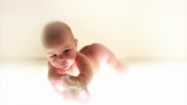 Infant playing with a plastic toy. White background.