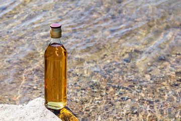 Bottle whiskey stands on stone in mountain river