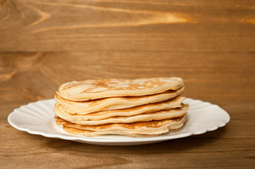 Pancake on the plate.  Wooden background.