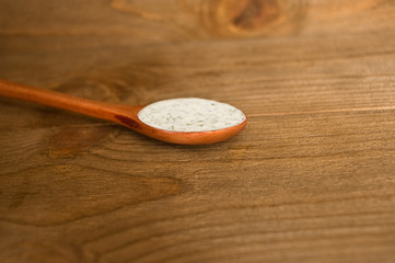 Sour cream sauce with dill in the wooden spoon. Wood background.