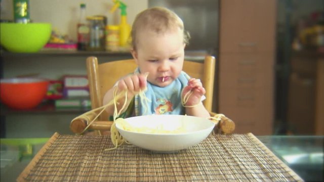 Funny child playing with spaghetti and sauce. Scene 2