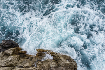 Fototapeta premium Danger sea wave crashing on rock coast with spray and foam windy storm in Autum Positano, Italy