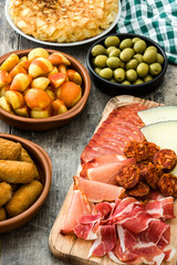 Traditional spanish tapas. Croquettes, olives, omelette, ham and patatas bravas on wooden table

