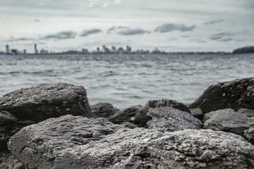 rocky seashore and dark stormy. On the horizon outlines of the big city and skyscrapers. blurred background. copy space for your text