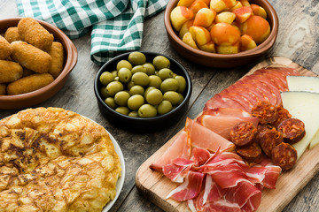 Traditional spanish tapas. Croquettes, olives, omelette, ham and patatas bravas on wooden table

