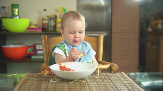 Funny child playing with spaghetti and sauce. Scene 5