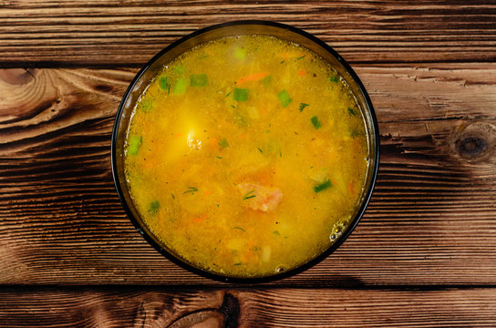 Vegetable soup in a glass bowl on wooden table. Top view