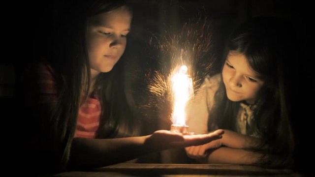 Girls performing magic, looking at a glowing fairy.  Fantasy, fairytale scene.