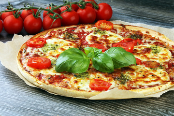 Hot true ITALIAN PIZZA with basil and cheese. TOP VIEW Tasty traditional pepperoni pizza on board on wooden table with decoration