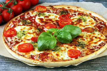 Hot true ITALIAN PIZZA with basil and cheese. TOP VIEW Tasty traditional pepperoni pizza on board on wooden table with decoration