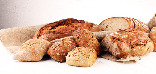 Different kinds of bread and bread rolls on board from above. Kitchen or bakery poster design.
