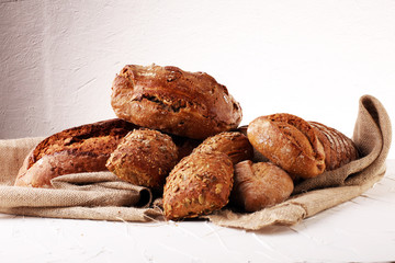 Different kinds of bread and bread rolls on board from above. Kitchen or bakery poster design.
