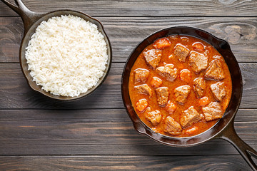Goulash traditional Hungarian beef meat stew soup spicy gravy food in cast iron pan with rice