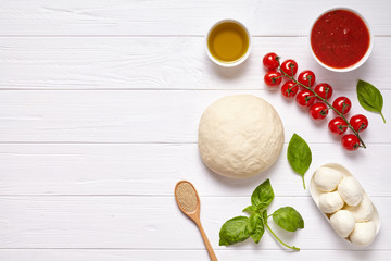 Pizza margherita traditional preparation recipe with baking ingridients: raw dough, cherry tomatoes, basil, tomato sauce and olive oil