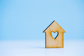 Obraz na płótnie Canvas Wooden house with hole in form of heart on blue background