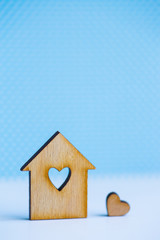 Obraz na płótnie Canvas Wooden house with hole in form of heart with little heart on blue background