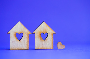 Obraz na płótnie Canvas Two wooden houses with hole in form of heart with little heart on blue background
