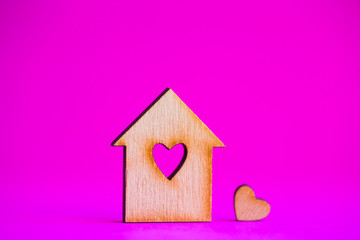 Obraz na płótnie Canvas Wooden house with hole in form of heart with little heart on crimson background