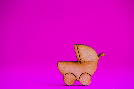Wooden icon of baby buggy on crimson background