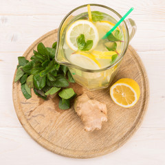 A glass decanter with a summer refreshing lemonade made of lemons and ginger with mint added on a...