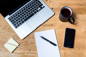 Work environment with a laptop, smartphone, notepad and other accessories on wooden table in a very accurate order. It is seen from above