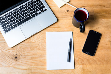 Work environment with a laptop, smartphone, notepad and other accessories on wooden table in a very accurate order. It is seen from above