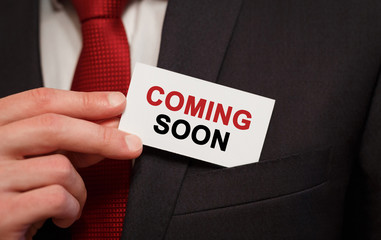 Businessman putting a card with text Coming Soon in the pocket