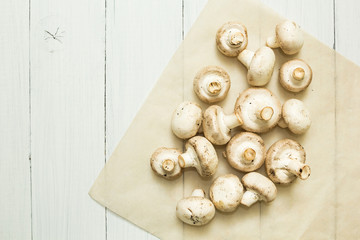 Fresh organic white mushrooms on a white wooden background, top view.