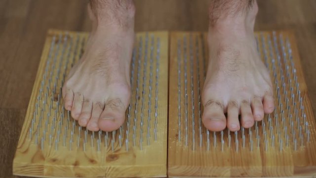 Closeup of yoga man stand on board with sharp nails