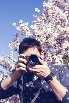 Hombre joven sacando fotos con su cámara en primavera 