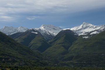 Landscape of mountains of a strong spring green, with snow-covered peaks after a strong thunderstorm of mountain, alps, italy