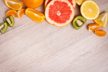 lemon, orange, kiwi, grapefruit, mandarin on a wooden surface. arrangement of sliced fruit. Top view with copy space for text