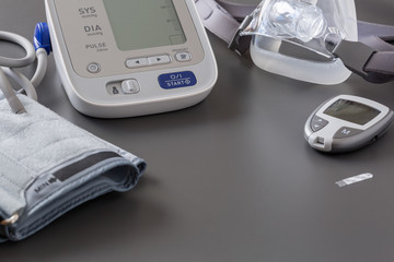 Electronic tonometer, mask and glucometer on the grey table