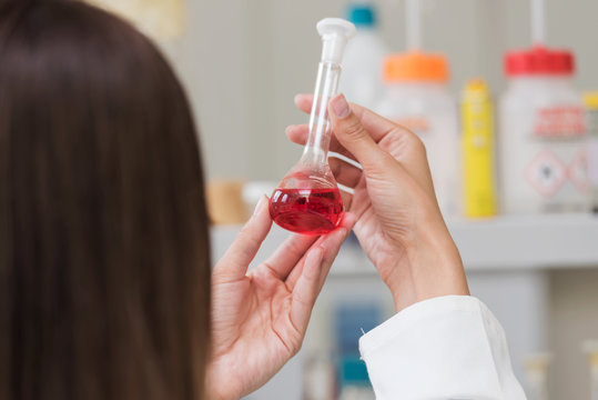 Woman scientist studying chemical liquid in lab flask. Scientist carrying out experiment in research laboratory