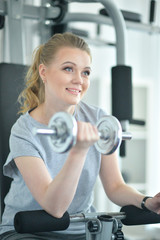 Obraz premium Young woman in a gym with a dumbbell