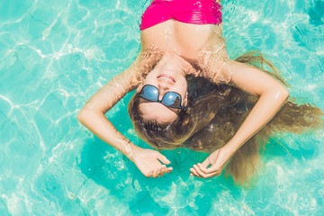 Beautiful young woman floating in pool relaxing Top view. Holiday concept
