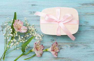 Flowers and a box with a gift on a turquoise background. The concept of a holiday